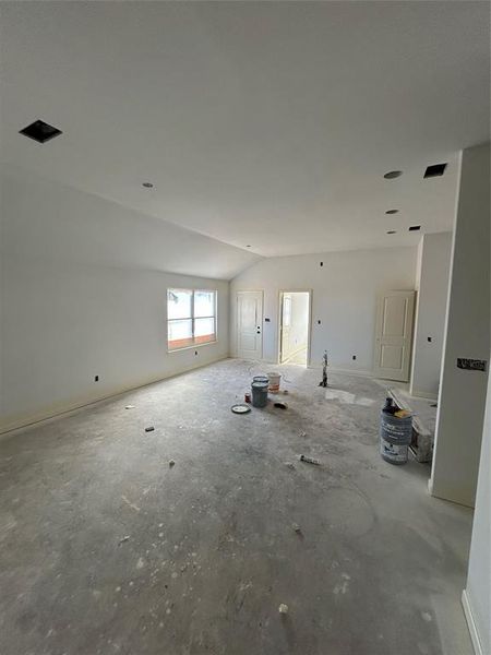 Unfurnished living room with lofted ceiling and baseboards