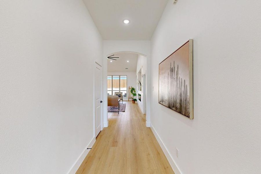 Hall featuring arched walkways, light wood finished floors, and recessed lighting