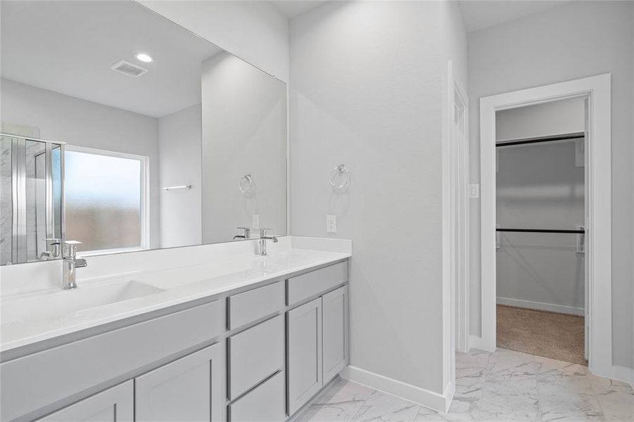 This primary bathroom is definitely move-in ready! Featuring light stained cabinets with dual vanities and light countertops, spacious walk-in closet with shelving, high ceilings, custom paint, sleek modern finishes.