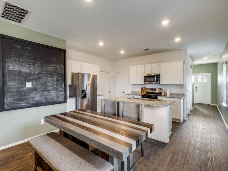 Kitchen featuring light stone counters, white cabinetry, appliances with stainless steel finishes, dark wood-style floors, and recessed lighting
