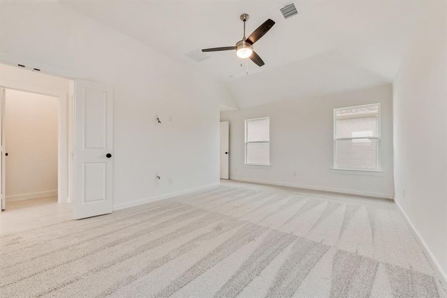 Unfurnished room featuring light colored carpet, lofted ceiling, and a ceiling fan Unfurnished room featuring light colored carpet, lofted ceiling, and a ceiling fan
