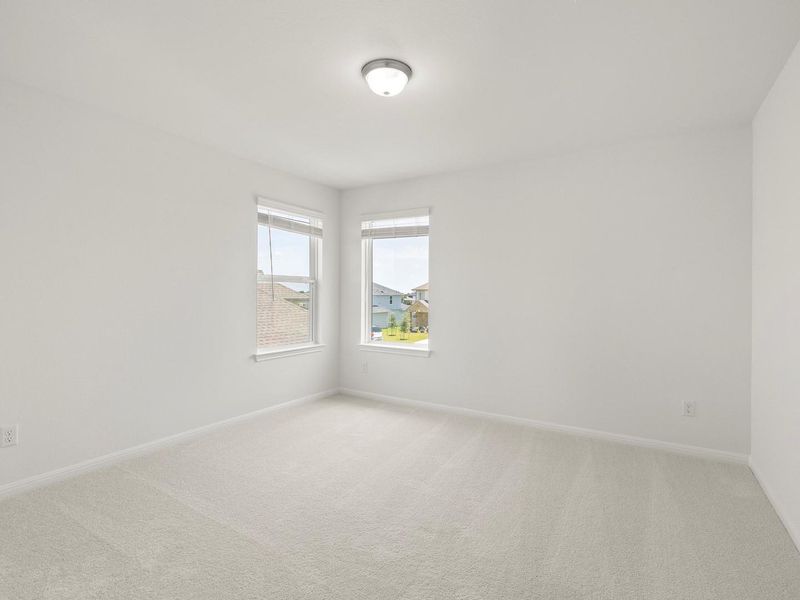 Two large windows provide abundant natural light in this comfortably carpeted room.