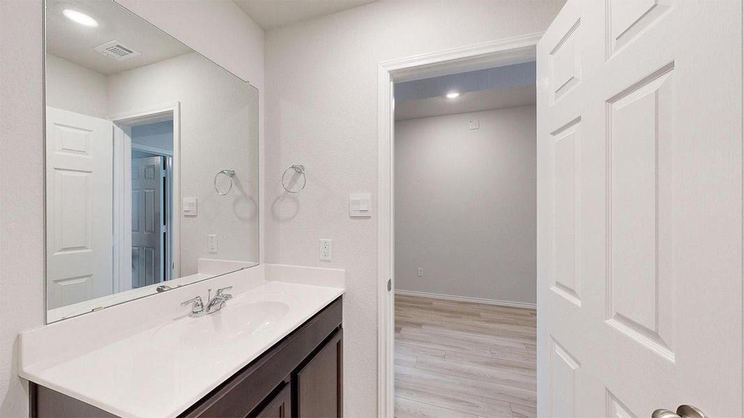 A well-appointed vanity with a crisp white countertop and dark cabinetry complements the bright, neutral tones of this inviting bathroom.