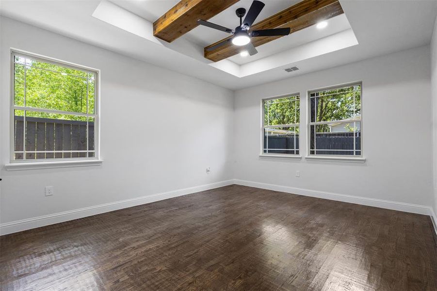 Unfurnished room with a ceiling fan, dark wood-style floors, a raised ceiling, and beamed ceiling Unfurnished room with a ceiling fan, dark wood-style floors, a raised ceiling, and beamed ceiling