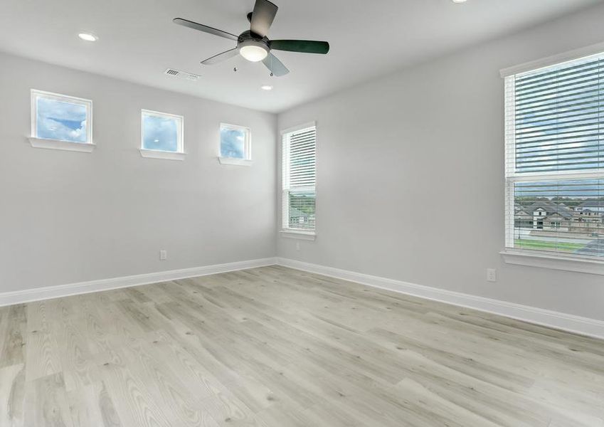 Spacious master bedroom with large windows, a ceiling fan, and wood flooring.