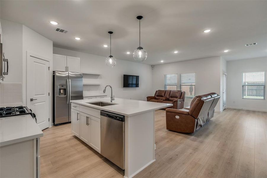 Kitchen with stainless steel appliances, open floor plan, open shelves, white cabinetry, and recessed lighting Kitchen with stainless steel appliances, open floor plan, open shelves, white cabinetry, and recessed lighting
