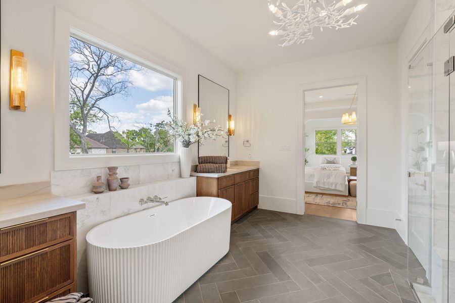 The primary bathroom showcases a spa-inspired layout with Mont Blanc quartzite countertops, dual vanities with reeded wood cabinetry, a freestanding soaking tub, and elegant wall-mounted fixtures.