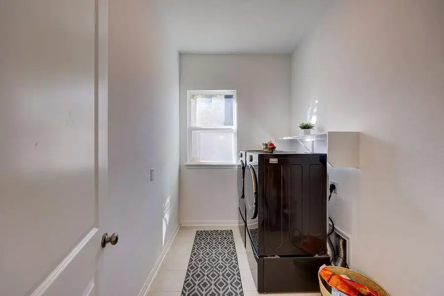 Washroom featuring light tile patterned flooring and washing machine and dryer