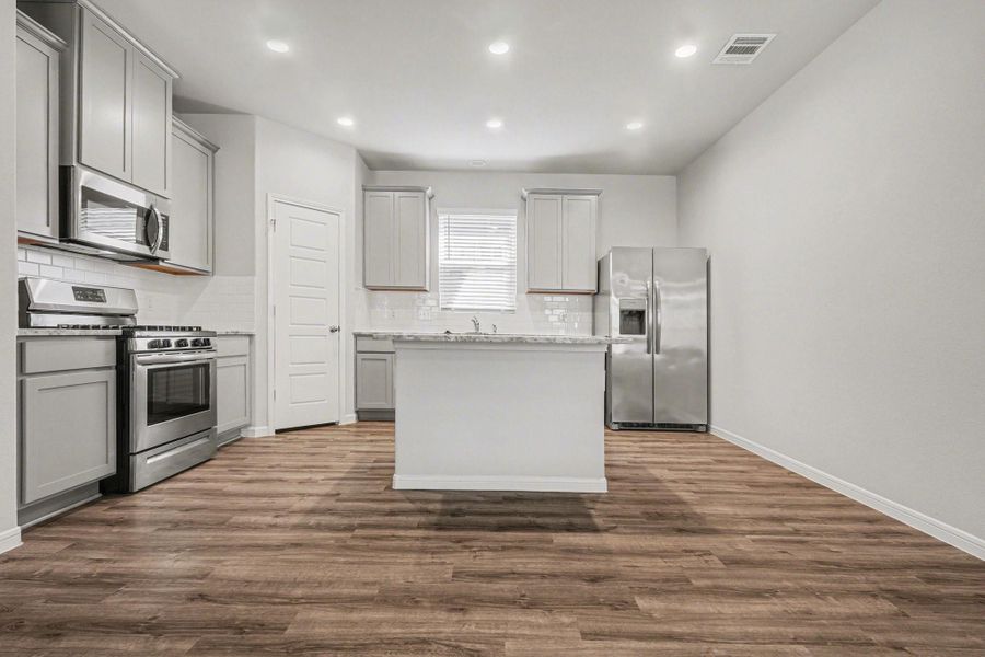 Light-filled kitchen with center island, granite countertops, and stainless steel appliances. Light-filled kitchen with center island, granite countertops, and stainless steel appliances.