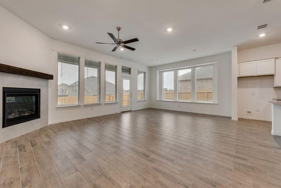 Unfurnished living room with ceiling fan, a fireplace, and light hardwood / wood-style flooring