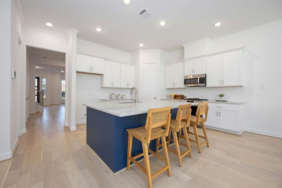 The crisp white countertops and backsplash paired with a contrasting blue island create a stunning culinary environment.