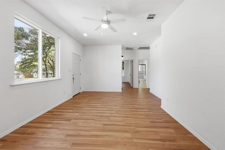 Large living room featuring light wood-type flooring, recessed lighting, and ceiling fan