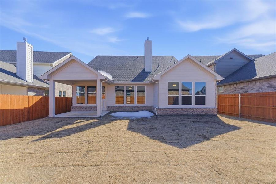 Rear view of property with a fenced backyard, a patio area, brick siding, and a chimney