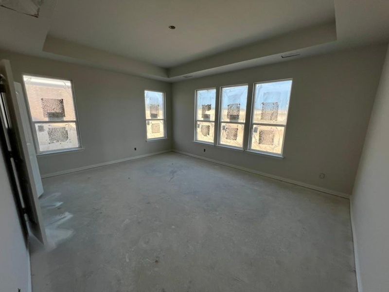 Empty room with a raised ceiling, concrete floors, and plenty of natural light