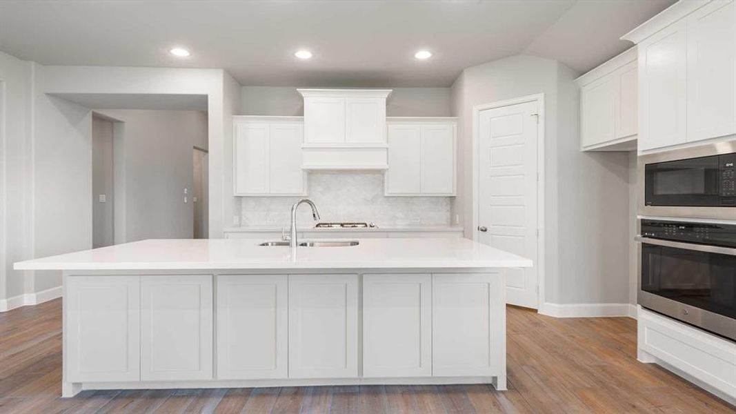 Kitchen with decorative backsplash, light hardwood / wood-style flooring, stainless steel oven, and black microwave