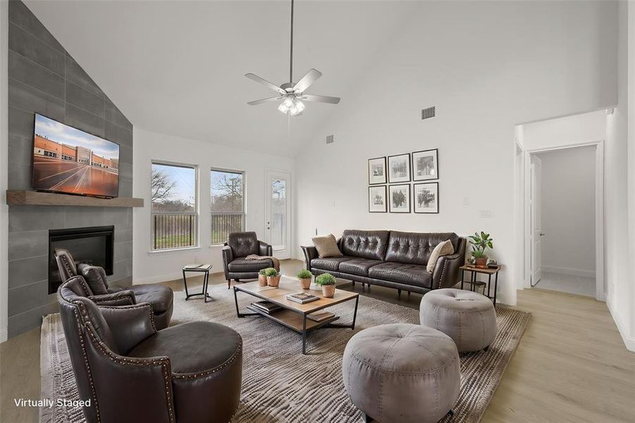 This living room has endless furniture placement possibilities. Rarely in an open floorplan, do you have large wall spaces to work with. The soaring ceilings, bright white walls, plank luxury laminate floors and wall of windows make this room feel even larger than it is. The floor to ceiling tile fireplace is a focal point for the room.