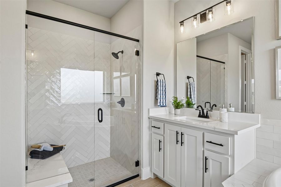 Bathroom with glass walk-in shower featuring herringbone tile, white vanity, and black fixtures Bathroom with glass walk-in shower featuring herringbone tile, white vanity, and black fixtures