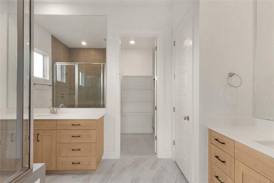 Bathroom with a stall shower, two vanities, recessed lighting, and a walk in closet