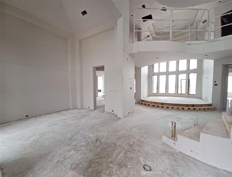 Grand Foyer view entering through the gorgeous double iron front doors with sites into the elegant Formal Dining Room, elevated two-story Living area, winding staircase and curved catwalk with lots of design appeal is coming along beautifully.