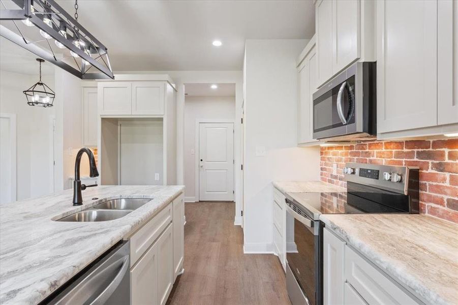 Kitchen featuring stainless steel appliances, light wood-style flooring, white cabinets, recessed lighting, and light stone countertops