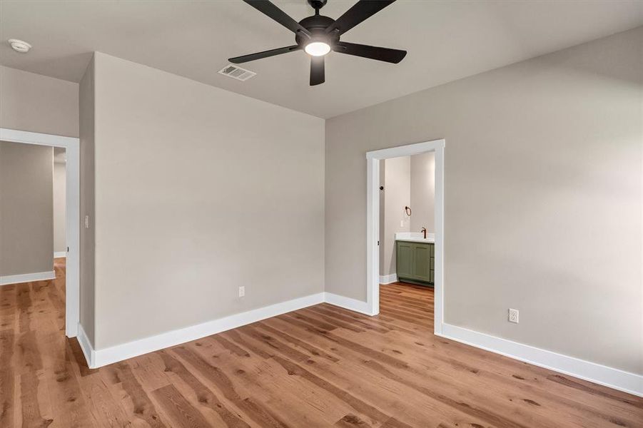 Unfurnished bedroom featuring light wood-style floors, ensuite bathroom, and ceiling fan Unfurnished bedroom featuring light wood-style floors, ensuite bathroom, and ceiling fan