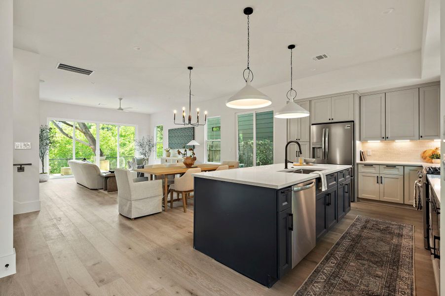 Kitchen featuring a sink, stainless steel appliances, open floor plan, decorative backsplash, and light countertops