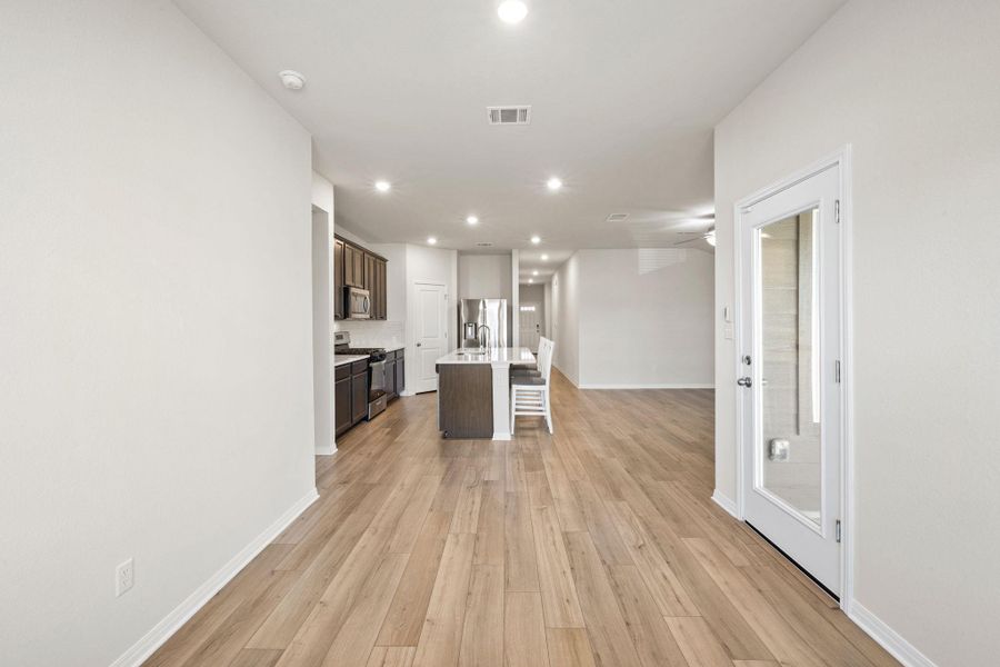 Kitchen with a kitchen island with sink, recessed lighting, dark brown cabinets, appliances with stainless steel finishes, and light wood-style flooring Kitchen with a kitchen island with sink, recessed lighting, dark brown cabinets, appliances with stainless steel finishes, and light wood-style flooring