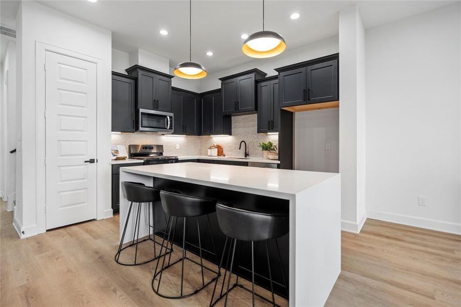 Modern kitchen with sleek black cabinets, a spacious island with seating, and stylish pendant lighting, offering a perfect blend of functionality and elegance. Modern kitchen with sleek black cabinets, a spacious island with seating, and stylish pendant lighting, offering a perfect blend of functionality and elegance.