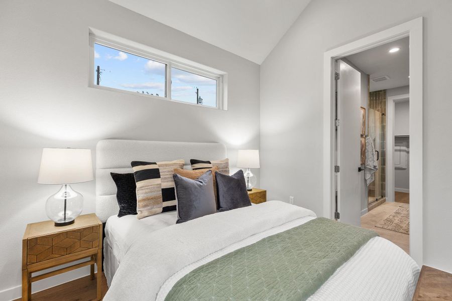 Bedroom featuring vaulted ceiling, baseboards, and wood finished floors