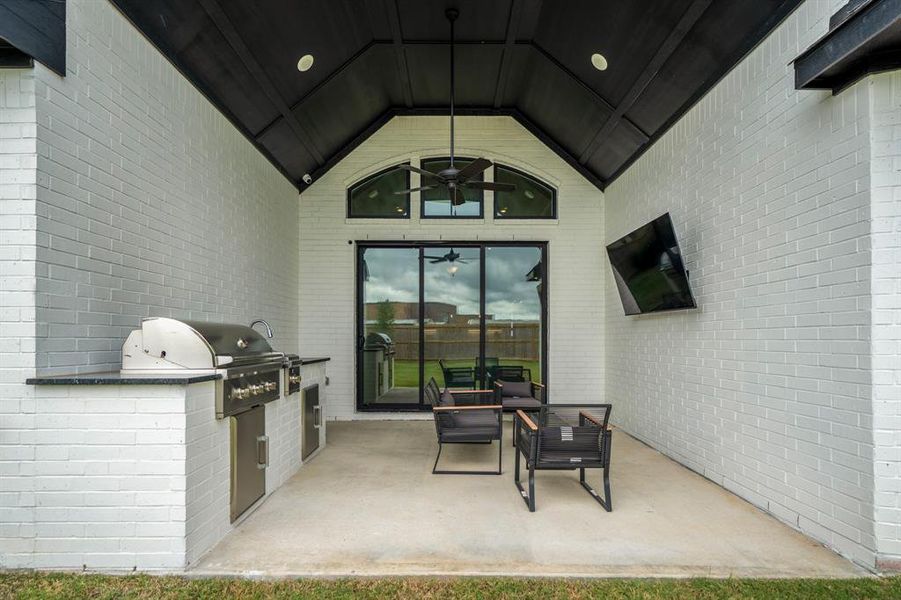 Head outisde to see the perfect outdoor patio space! It features an outdoor kitchen, vaulted ceilings with overhead stain wood panels, ceiling fan, and sliding glass doors connecting to the main living are making it perfect for indoor-outdoor living.