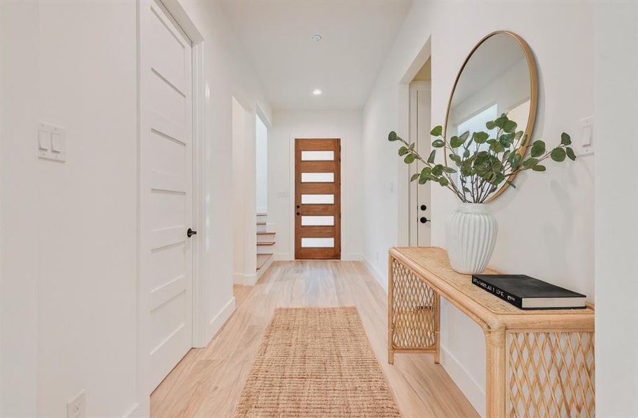 Doorway with light wood finished floors and recessed lighting