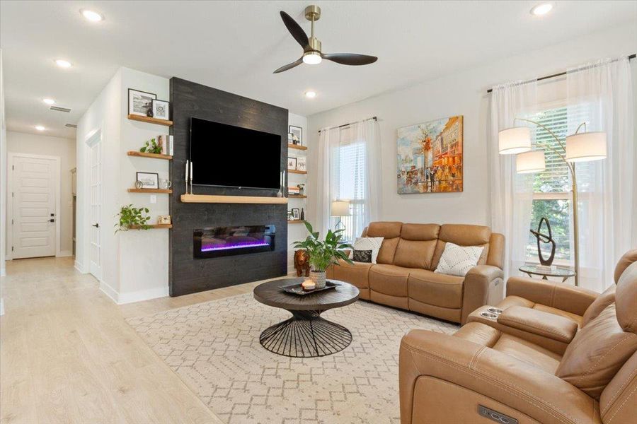 Living room featuring ceiling fan, light wood finished floors, a glass covered fireplace, and recessed lighting