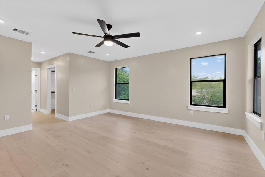 A tranquil primary bedroom with light wood flooring and contemporary ceiling fan offers a peaceful retreat.