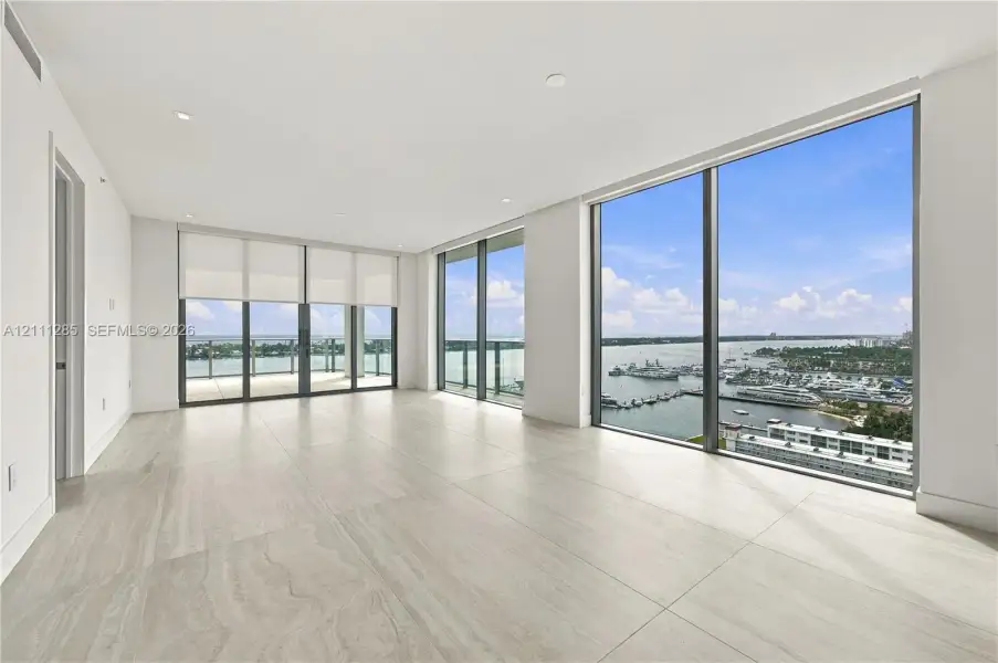 Expansive living area featuring floor-to-ceiling windows, large-format tile flooring, recessed lighting, and a private balcony Expansive living area featuring floor-to-ceiling windows, large-format tile flooring, recessed lighting, and a private balcony