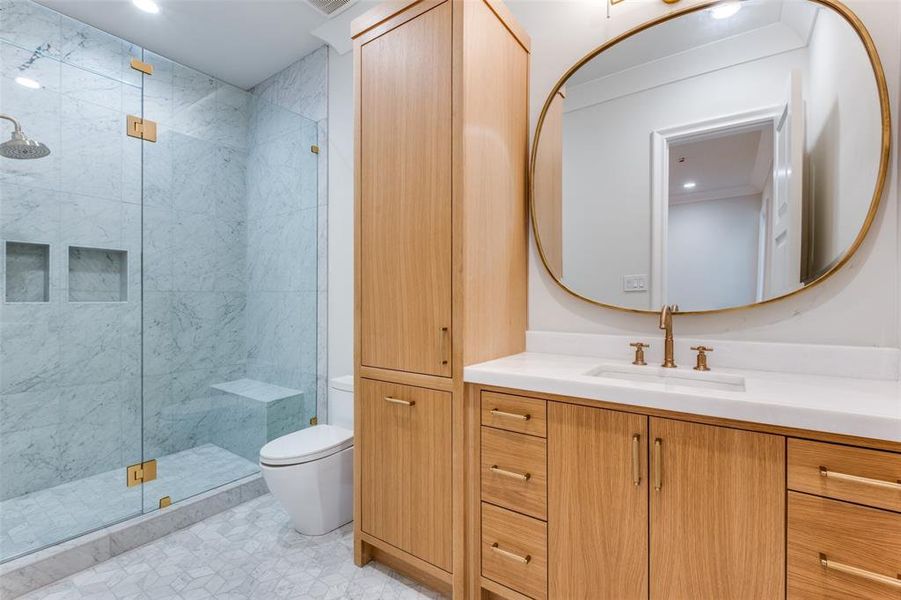 Bathroom featuring a shower with door, vanity, and toilet