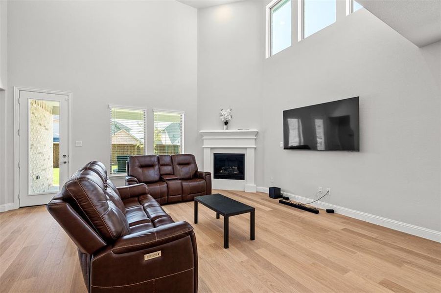 Living room with light hardwood / wood-style flooring and a towering ceiling