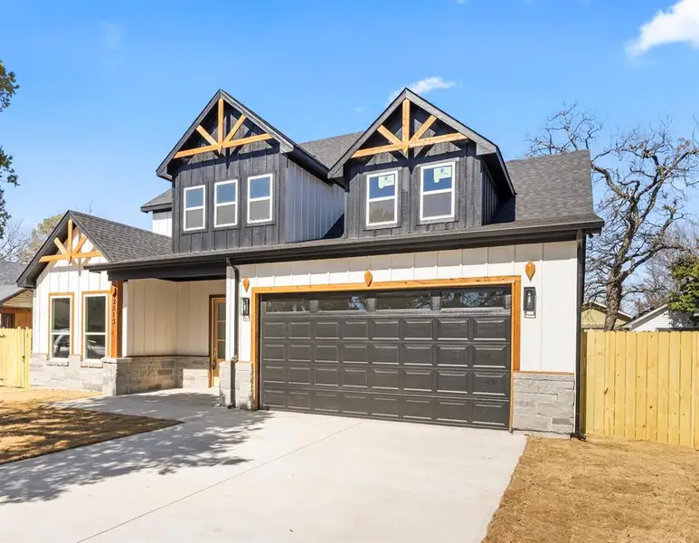 View of front facade featuring roof with shingles, concrete driveway, covered porch, stone siding, and an attached garage View of front facade featuring roof with shingles, concrete driveway, covered porch, stone siding, and an attached garage