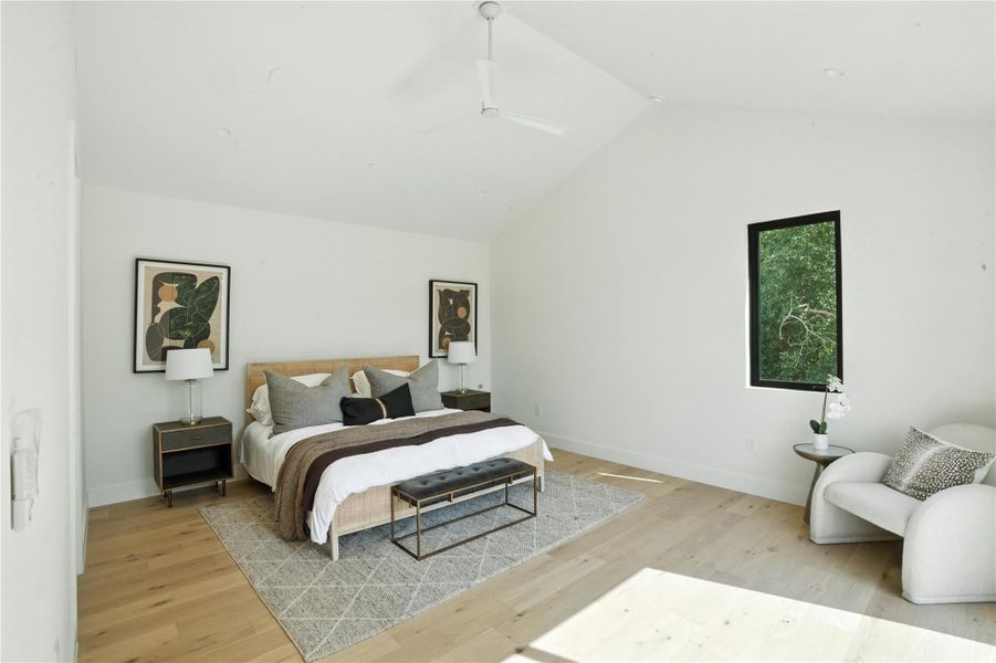 Bedroom featuring lofted ceiling, light wood-type flooring, and a ceiling fan Bedroom featuring lofted ceiling, light wood-type flooring, and a ceiling fan