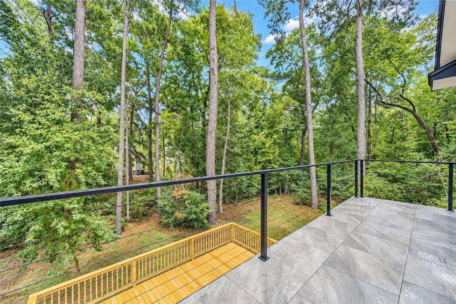 Enjoy serene views from this spacious balcony overlooking a lush, wooded landscape, perfect for nature lovers seeking tranquility.