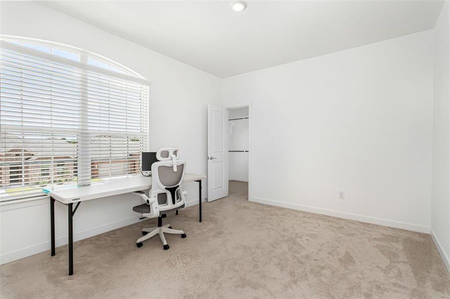 Carpeted 2nd floor bedroom featuring a large arched window with blinds, a recessed ceiling light, and a white interior door