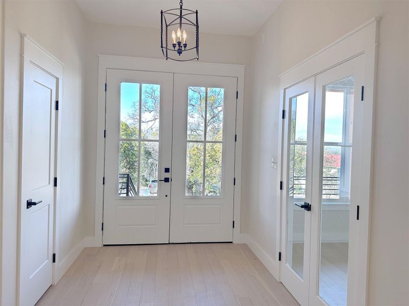 Front Entry Doorway to outside with french doors, oak hardwood floors, and a stylish chandelier