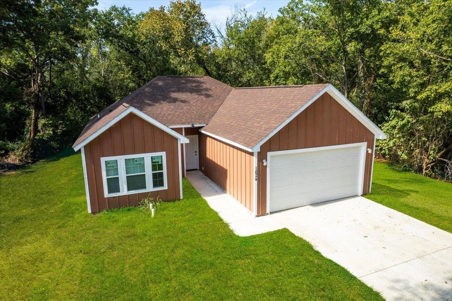 View of front of house featuring a shingled roof, a front yard, a garage, and board and batten siding View of front of house featuring a shingled roof, a front yard, a garage, and board and batten siding