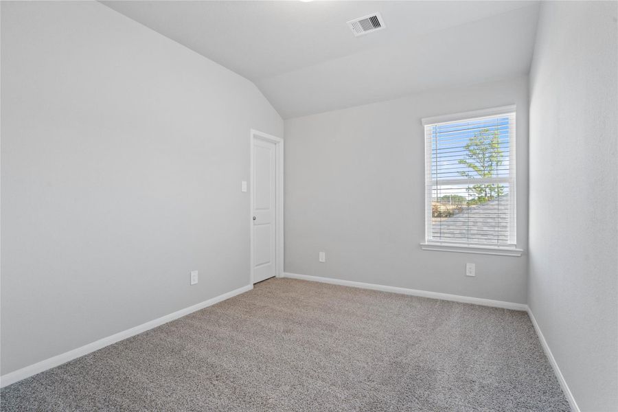 Step into this bright and airy secondary bedroom! It offers a tranquil space to unwind. The large window illuminates the room's sloped ceiling and neutral tones, creating a cheerful and airy environment. This room also features a walk-in closet.