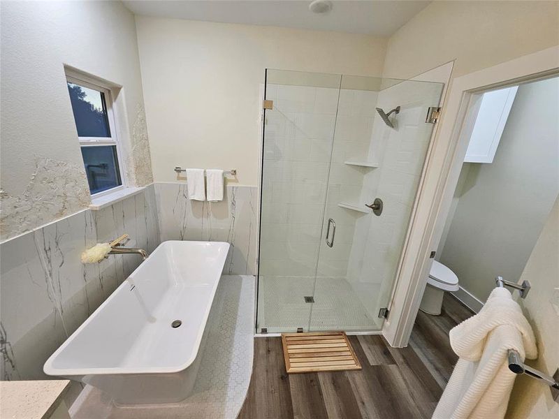 Master bathroom, soaking bathtub and tile underneath, and independent custom glass shower doors in the shower.