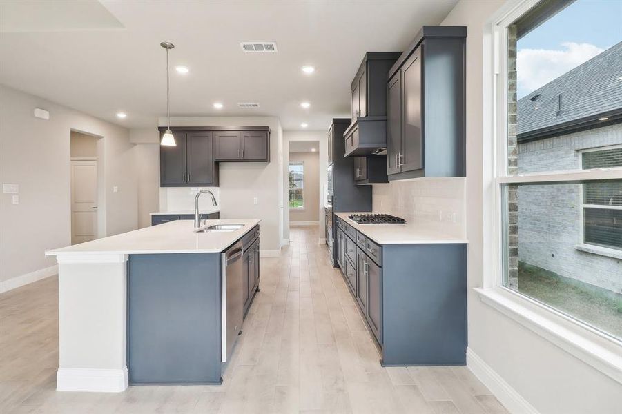 Kitchen with a kitchen island with sink, sink, pendant lighting, and plenty of natural light