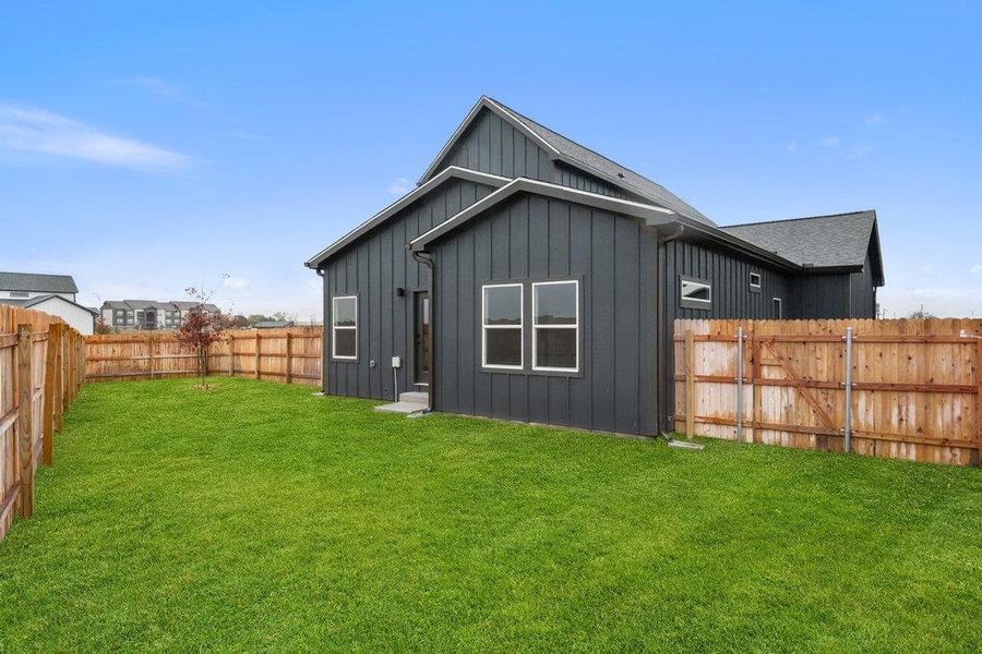 Rear view of house featuring board and batten siding and a fenced backyard