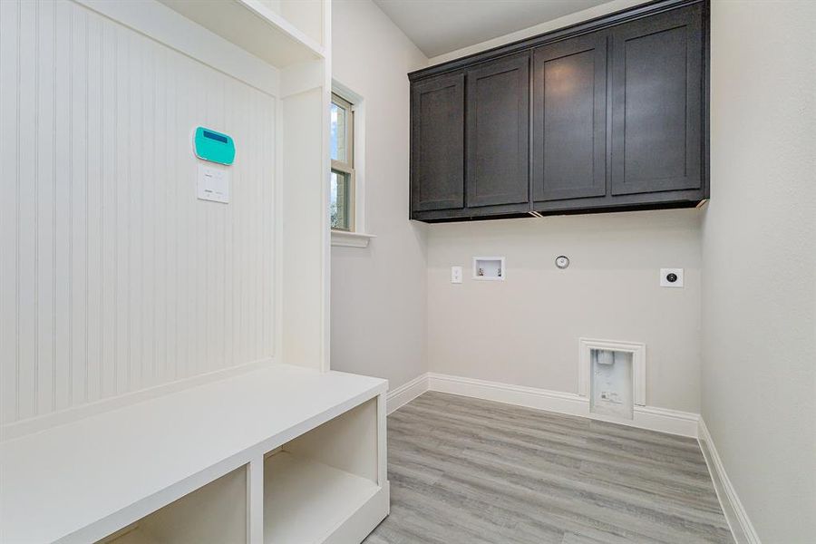 Washroom featuring hookup for an electric dryer, hookup for a washing machine, light wood-type flooring, cabinets, and gas dryer hookup