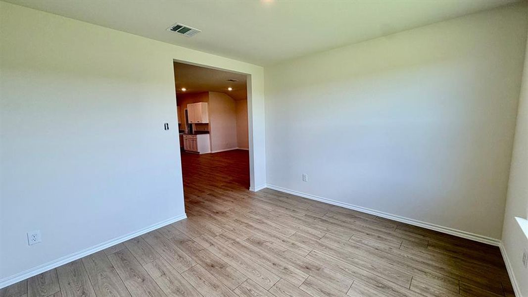 Spacious room featuring wood-finish flooring, white baseboards, and neutral wall paint