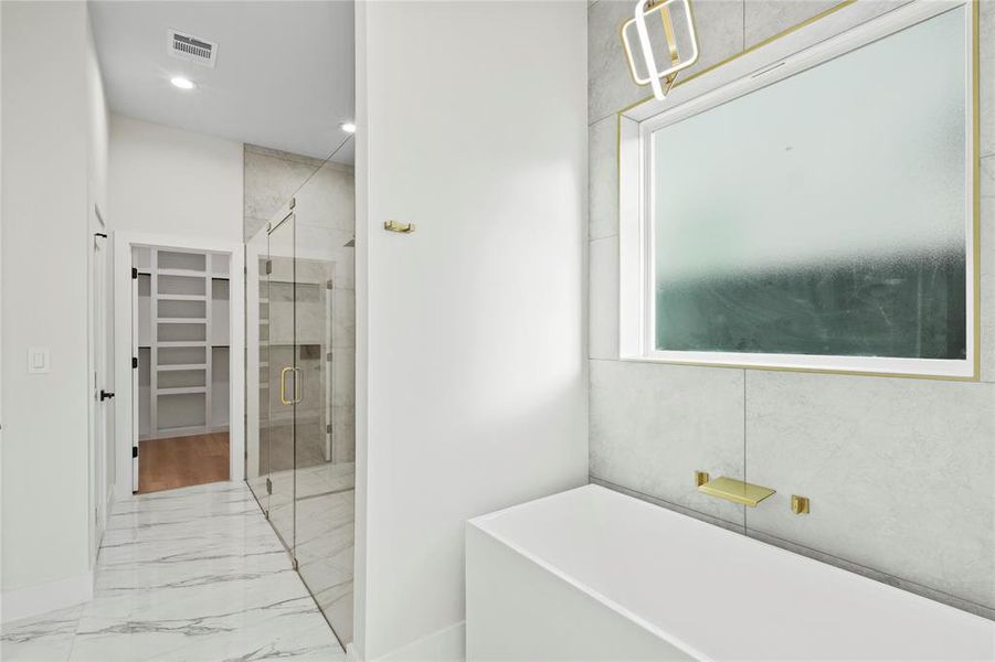 Bathroom featuring visible vents, a soaking tub, marble finish floor, a walk in closet, and a shower stall