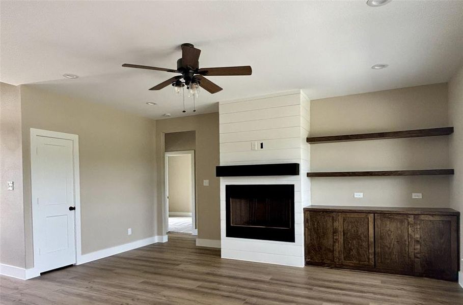 Unfurnished living room with a fireplace, a ceiling fan, dark wood-style floors, and recessed lighting